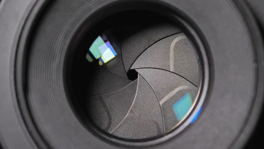 Shot of Diaphragm blades of fixed camera lens opening and closing aperture. Closing and opening Aperture of film camera. Camera lens aperture close-up.