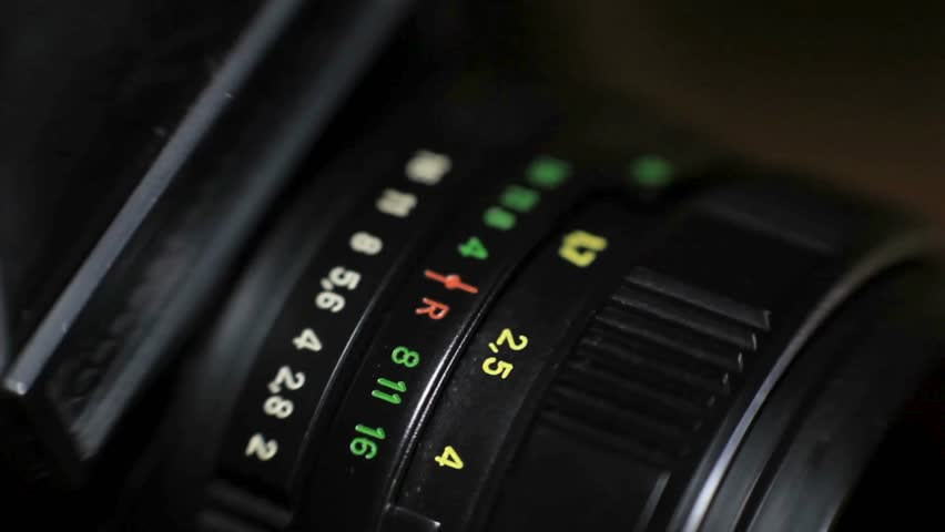 Detail on the lens scale of a film camera while the zoom wheel is turning. Macro-shot of a camera lens focus scale. Adjusts the camera Manual Aperture.
