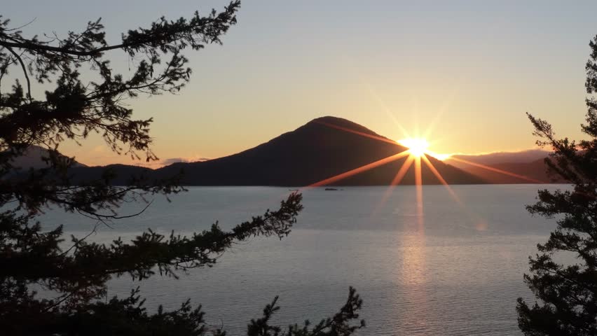 Radiant Sunset Over a Mountain Lake with Silhouetted Pine Trees in British Columbia, Canada