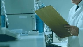 Senior tech reading clipboard operating device for lab tests while purple hexagon overlaying scene. Scientist, laboratory, chromatography, instrumentation, benchtop, research, digital - Powered by Shutterstock - Get 15% off with code: PIKWIZARD15