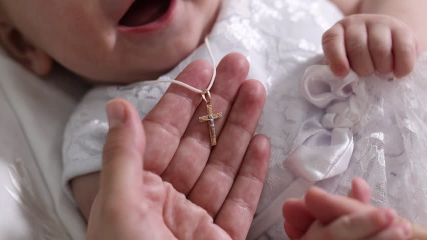 Sacrament of baptism. Woman putting gold cross on little baby indoors, closeup