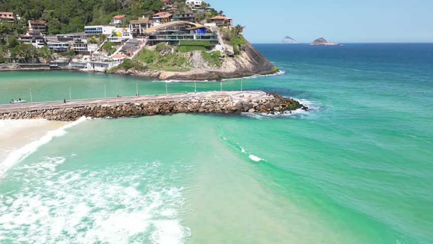 A breathtaking aerial view of Rio de Janeiro, featuring lush mountains, vibrant blue ocean, city streets, boats, and rooftops under a clear sky.  
Perfect blend of nature and urban life captured in on