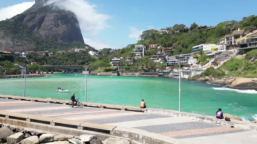 A breathtaking aerial view of Rio de Janeiro, featuring lush mountains, vibrant blue ocean, city streets, boats, and rooftops under a clear sky.  
Perfect blend of nature and urban life captured in on