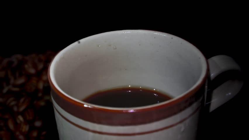 Close-up of Coffee Pour Into Cup with black background. Beverage stream. Slow motion