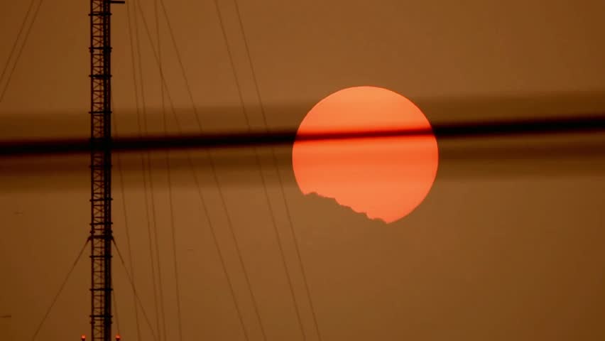 Sunset behind clouds and tower creating a warm and atmospheric silhouette view
