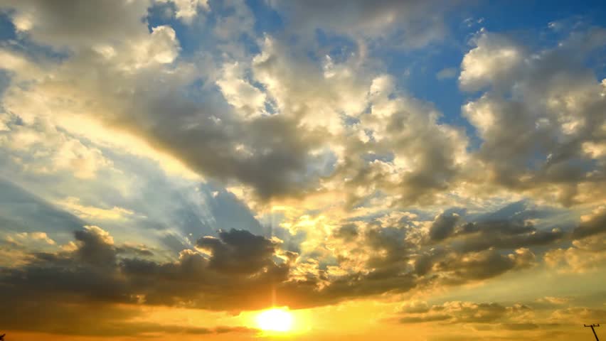 Dramatic sunset sky with sunbeams shining through clouds creating a peaceful scene