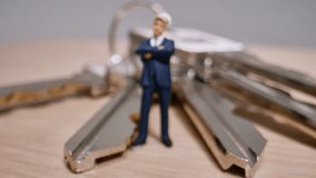 Miniature Businessman Figure Stands On House Keys, Representing Real Estate Investment And Ownership (Macro Shot). - Powered by Shutterstock - Get 15% off with code: PIKWIZARD15