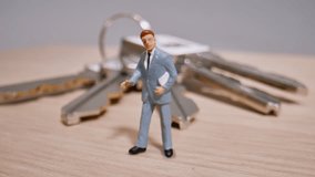 A Miniature Businessman Figurine Stands On A Wooden Table In Front Of House Keys, Symbolizing Property Ownership And Investment. - Powered by Shutterstock - Get 15% off with code: PIKWIZARD15