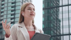 Professional young caucasian businesswoman talking using wireless earbud while holding digital tablet outdoors in city, business woman using technology for communication and success in urban. - Powered by Shutterstock - Get 15% off with code: PIKWIZARD15