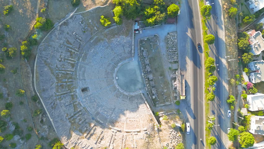 Bodrum, Turkey. Elevated drone shot of classical amphitheater structure. Ancient performance space with tiered stone seating on mountain slope. Aerial View, MasterShots, Tilt up, Tilt down