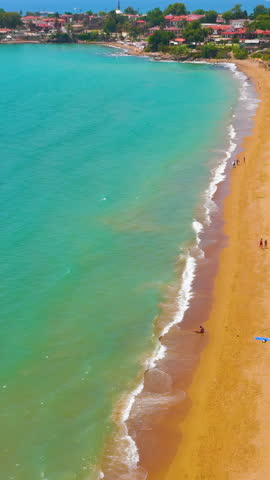 Vertical video. Side, Manavgat, Turkey. Ancient Agora and Roman amphitheater with crane, Temple of Tyche, colonnaded street, beach at archaeological site on sunny day. Aerial View. Rich colors