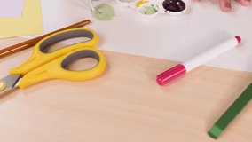 Hand mixes watercolor paints with brush on palette, surrounded by art supplies, under bright lighting - Powered by Shutterstock - Get 15% off with code: PIKWIZARD15