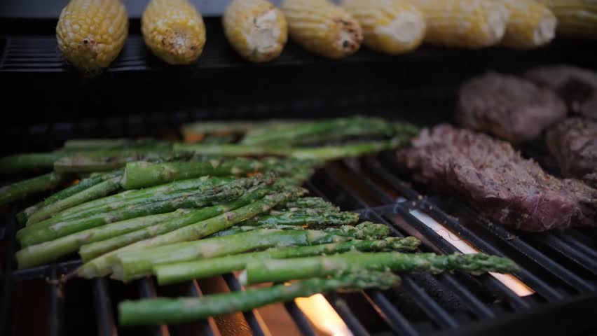 Fresh asparagus cooking on a BBQ grill in slow motion, highlighting vibrant vegetables, outdoor cooking, and healthy food preparation.
