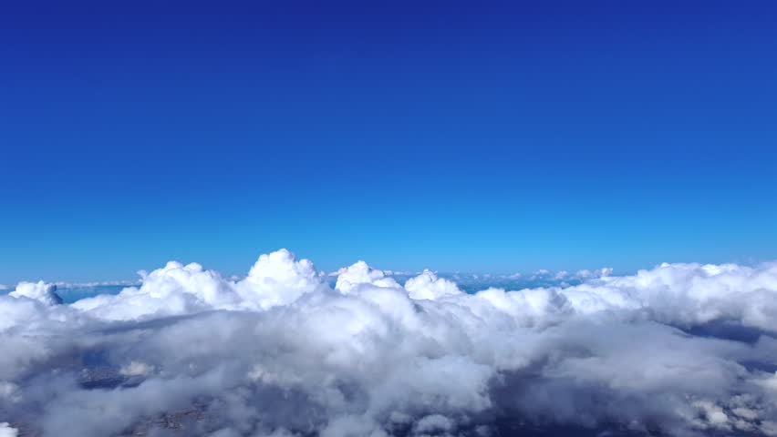 An immersive fighter jet pilot´s view while flying above some cottony clouds climbing in a adeep blue sky.