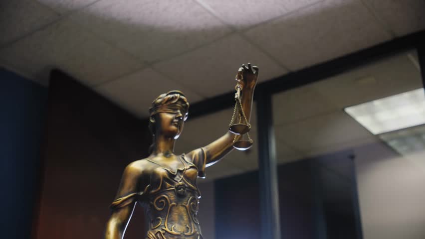 Statue of Lady Justice on a neutral background, symbolizing law and justice, captured with smooth camera movement for professional legal context.