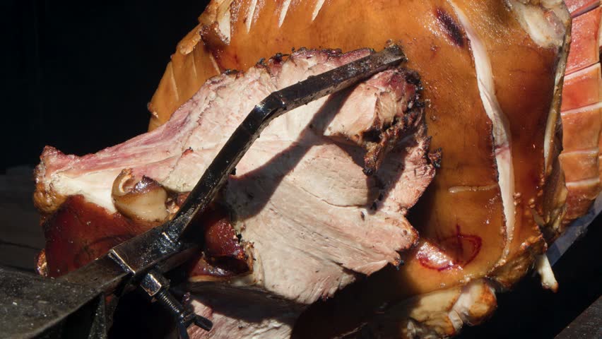 Whole pork roasting on spit over open flame, golden skin, classic Prague street food.