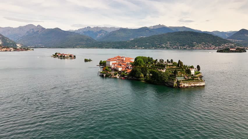 Drone view of Sresa Isola Bella Italy featuring a lakeside island with elegant buildings, terraced greenery, and surrounding mountain landscape under soft daylight across calm waters and scenic views