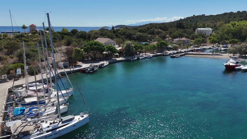 Kastos Island,Aerial view backwards from the sun soaked town quay, Crystal clear water in the Harbor.Lot of boats and the Greek flag