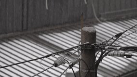 Rain falls over a worn concrete utility pole with tangled electrical cables and connectors, while a corrugated metal roof in the background forms soft lines and muted tones in the dim overcast weather - Powered by Shutterstock - Get 15% off with code: PIKWIZARD15