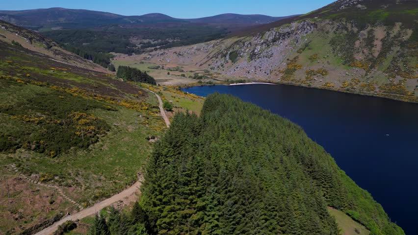 Smooth forward-moving aerial shot over rugged hillsides and deep blue waters at Lough Dan in County Wicklow, Ireland, capturing the serene landscape and sweeping natural beauty of the valley