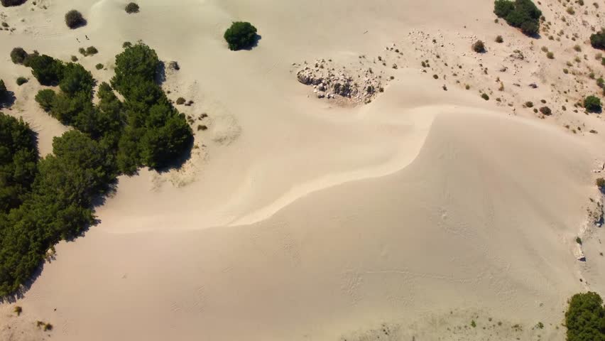 aerial perspective captures the vast, undulating sand dunes of Patara, Turkey, near the ancient Lycian city and its renowned beach. This footage showcases the unique desert-like landscape meeting the