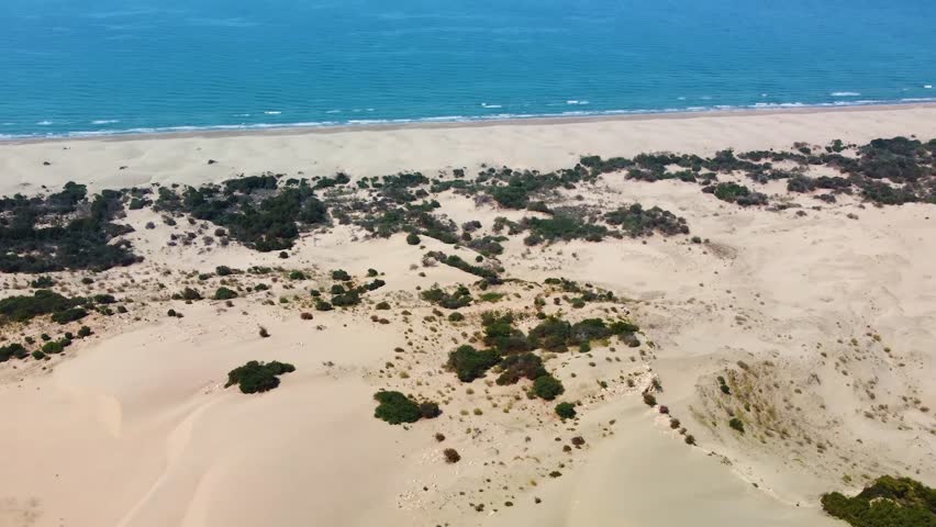 Drone footage captures the aerial view of the Patara Sand Dunes meeting the pristine Mediterranean Sea in Antalya Province, Turkey.