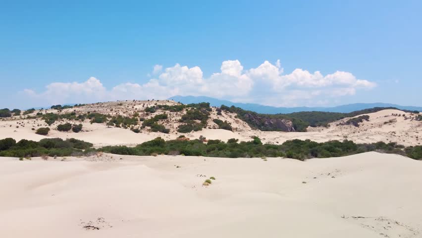 Aerial footage showcasing the vast, golden sand dunes of Patara, Turkey, stretching towards the pristine Mediterranean Sea. The video captures the unique desert like landscape meeting the azure waters