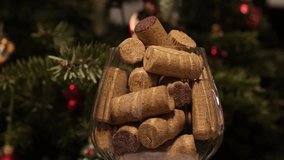 An overflowing glass with red wine corks and champagne stopper on the background of a Christmas tree. Concept of alcohol abuse during the Christmas holidays. 4K video, turntable, glass rotating. - Powered by Shutterstock - Get 15% off with code: PIKWIZARD15