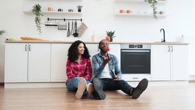 A happy couple is sitting on the floor in a modern kitchen, with the man juggling apples. - Powered by Shutterstock - Get 15% off with code: PIKWIZARD15
