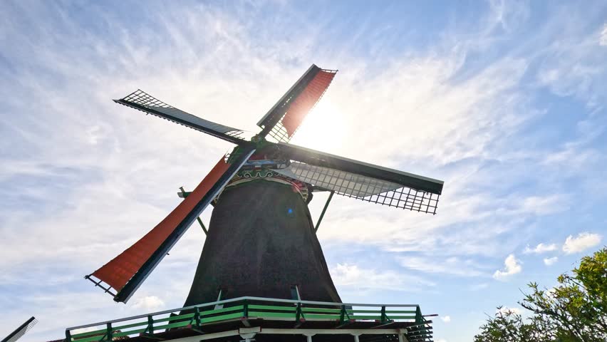 Historic windmill blades turning in sunlight, low angle, vibrant blue sky, Zaandam, Netherlands