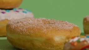 Close up of donuts stacked on each other against a green background. Donuts have sugar and sprinkles. Sweet treat concept. - Powered by Shutterstock - Get 15% off with code: PIKWIZARD15