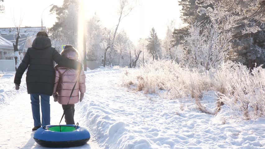 Mother with daughter walking together. Toboggan hill, Family outdoors in winter on sledge . Family winter time. Recreational pursuit	