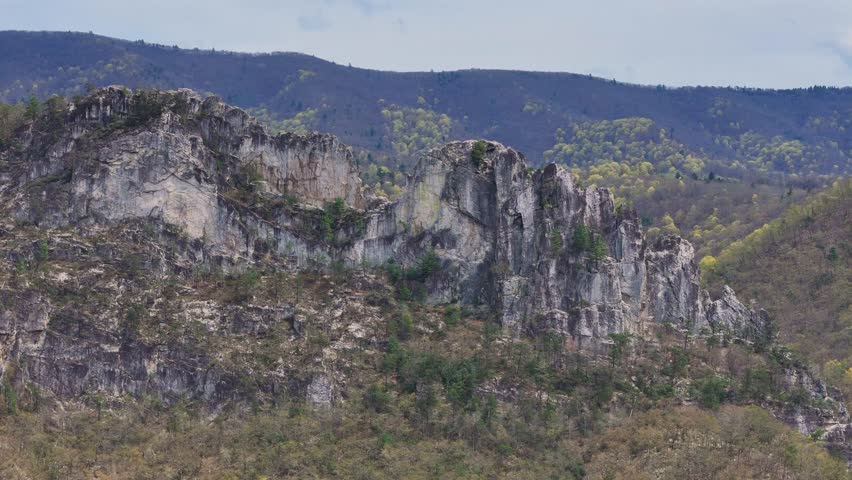 Vertical cliffs of Seneca Rocks viewed from side with forested mountain backdrop, West Virginia, USA