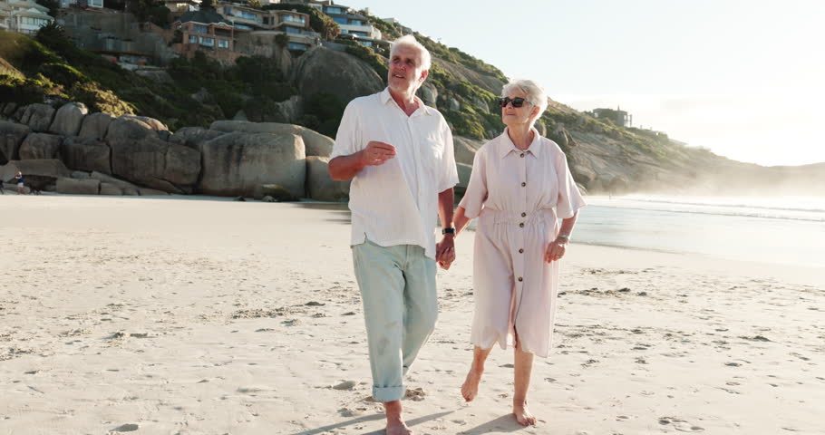Elderly couple, walking or holding hands on beach for outdoor date, bonding or sightseeing together. Senior, woman and man pointing with view for retirement holiday, travel or vacation on ocean coast
