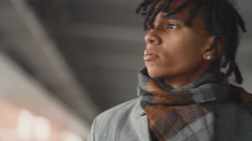 Portrait of depressed and frustrated black man on city street in autumn day. Worried african american student waiting someone under bridge, urbanistic landscape, diversity of people appearance
