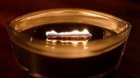 A wooden-wick candle burns in a dark room, its flame crackling like a small fireplace within an ellipse glass vessel, creating a warm and inviting winter ambience. - Powered by Shutterstock - Get 15% off with code: PIKWIZARD15