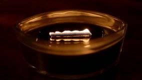 Still shot of a wooden-wick candle burning in darkness. Its long, dancing flame crackles like a fireplace inside a modern ellipse glass vessel, creating a warm, cozy winter atmosphere. - Powered by Shutterstock - Get 15% off with code: PIKWIZARD15