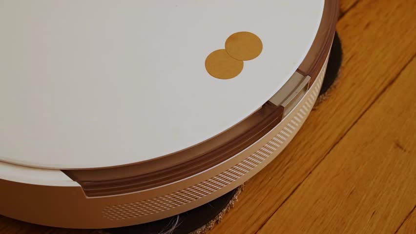 Extreme close-up shot of the front bumper and top panel of a white robotic vacuum cleaner, highlighting the navigation sensor window and the operational status indicator lights.