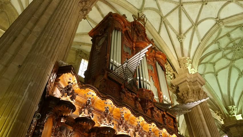 Pipe organ and carved wood in the Guadix Cathedral. Low-angle view of the musical instrument, religious architecture and Baroque details in Granada, Spain.