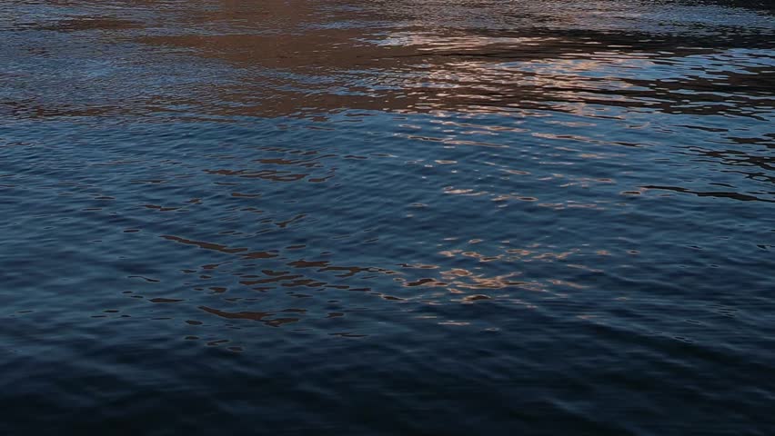 Bright blue water reflects the majestic Alps in Italy under a clear sky. The drone captures the serene landscape, showcasing nature