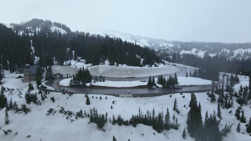 Aerial drone shot flying over the snowy mountains of Mount Rainier during winter, showcasing a vast white landscape.