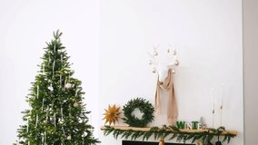Decorated evergreen tree next to fireplace mantel with winter greenery and reindeer head decor - Powered by Shutterstock - Get 15% off with code: PIKWIZARD15