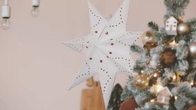 White festive star decoration hangs near a decorated Christmas tree with golden baubles indoors. - Powered by Shutterstock - Get 15% off with code: PIKWIZARD15