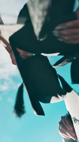 Graduation, below and students with cap in air for education success, milestone and achievement. University, high five and hands of friends throw for celebration, learning and applause on blue sky