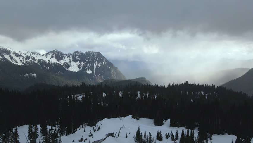 Aerial drone shot flying over the snowy mountains of Mount Rainier during winter, showcasing a vast white landscape.