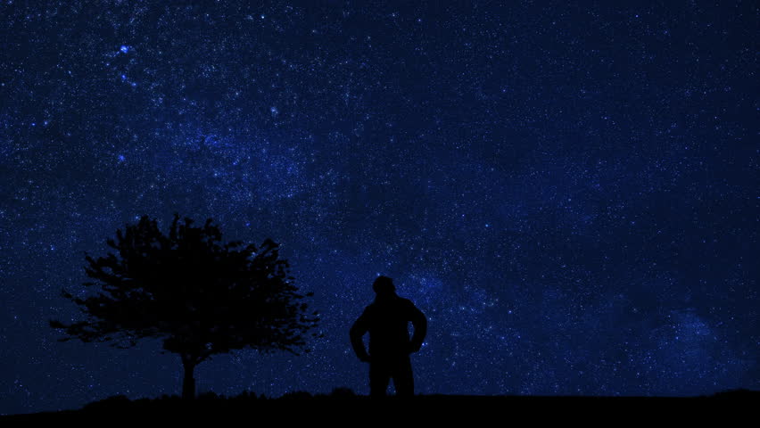 Silhouette of a man and countryside under the Milky Way stars.	