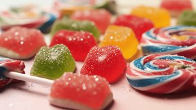 Close-up of a Colorful Assortment of Sugar-Coated Jelly Candies and Swirl Lollipops on a Light Pink Background - Powered by Shutterstock - Get 15% off with code: PIKWIZARD15