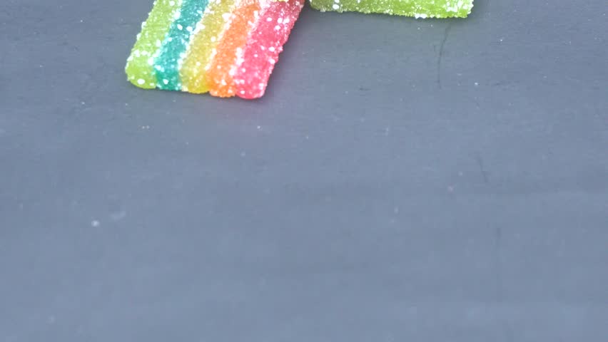 Colorful sour rainbow belts candy with vibrant sugar coating, offering tangy flavor, chewy texture, and eye-catching striped design for fun treats