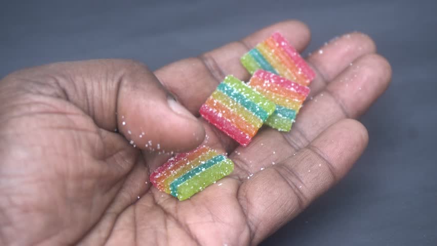Colorful sour rainbow belts candy with vibrant sugar coating, offering tangy flavor, chewy texture, and eye-catching striped design for fun treats