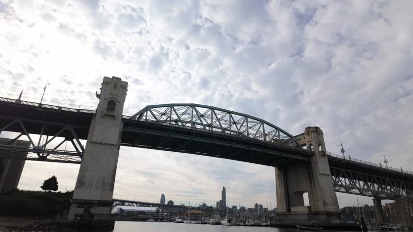 Gimbal wide booming down shot of the Burrard Bridge spanning False Creek on an autumn day in Vancouver, British Columbia, Canada. 4K